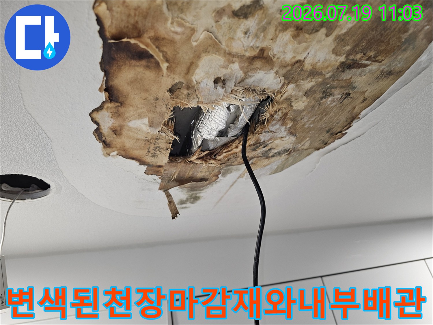습기로 인해 갈색으로 변하고 찢어진 천장-내부에 은색 단열재가 노출된 상태