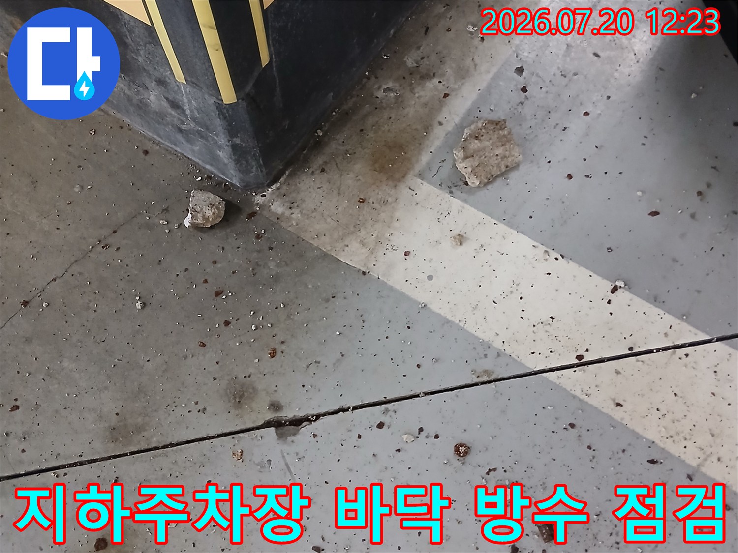지하 주차장 바닥의 균열과 배관 주변 노출된 콘크리트와 오염 상태
