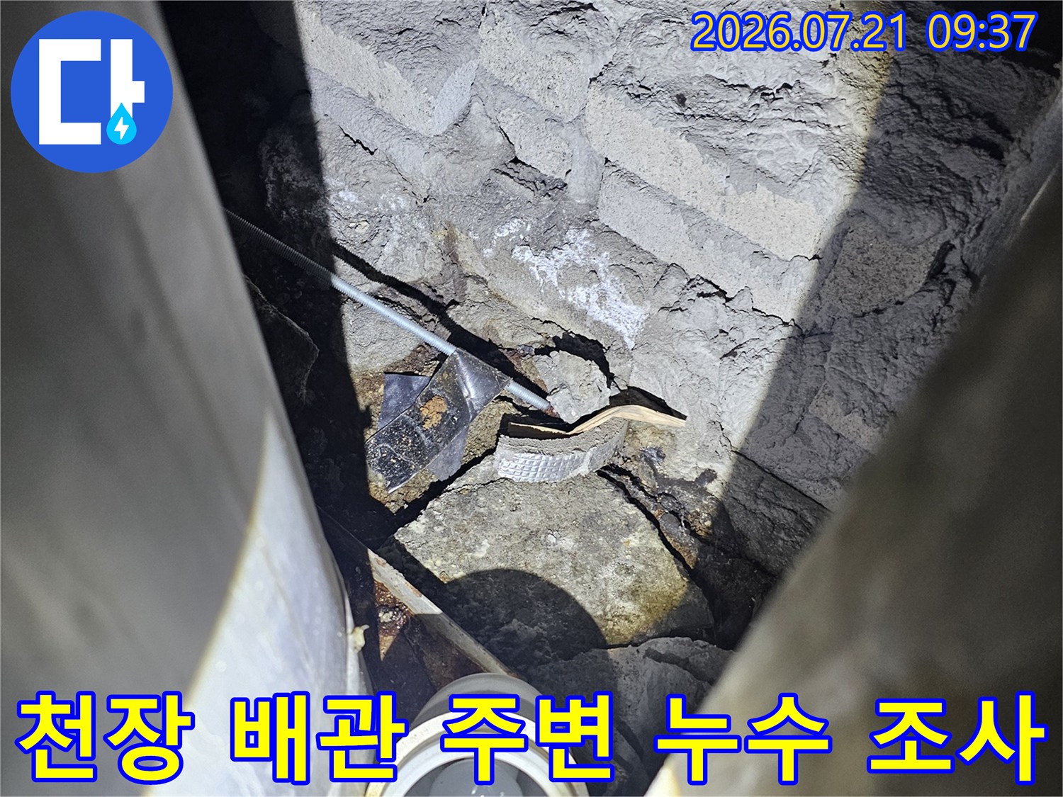 지하 주차장 천장의 노출된 배관과 콘크리트 경계면을 상세히 점검하는 모습