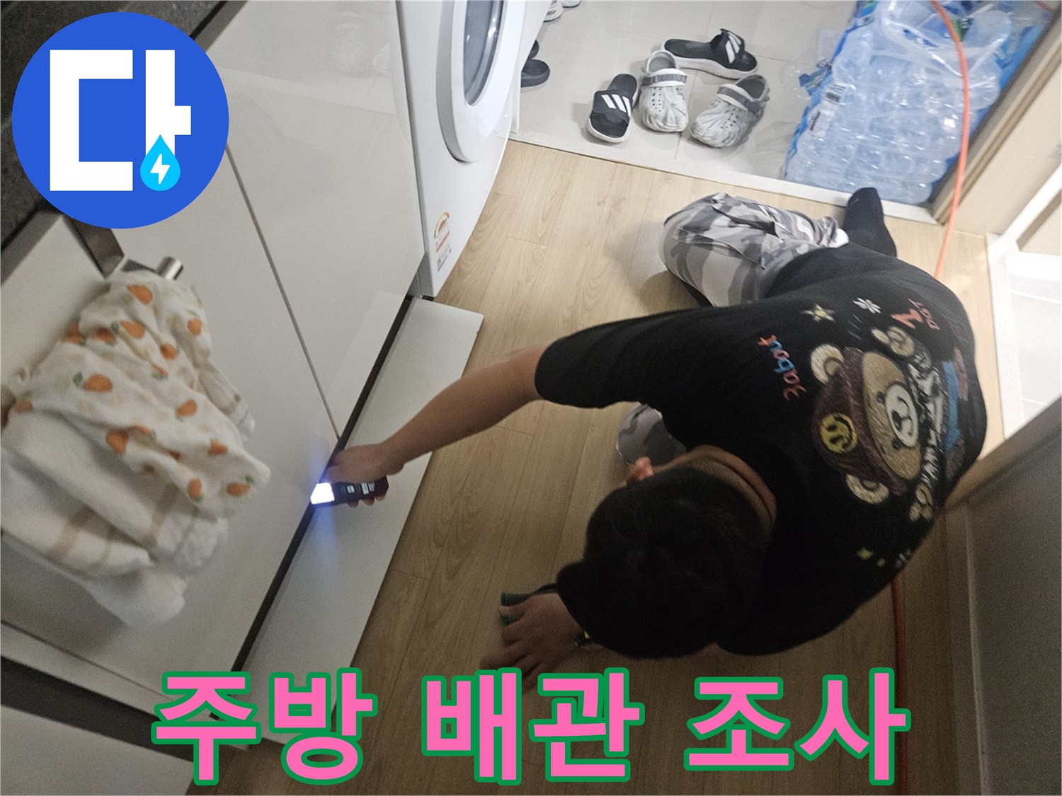 손전등을 비춰 싱크대 하단 배관의 누수 흔적을 찾는 작업자