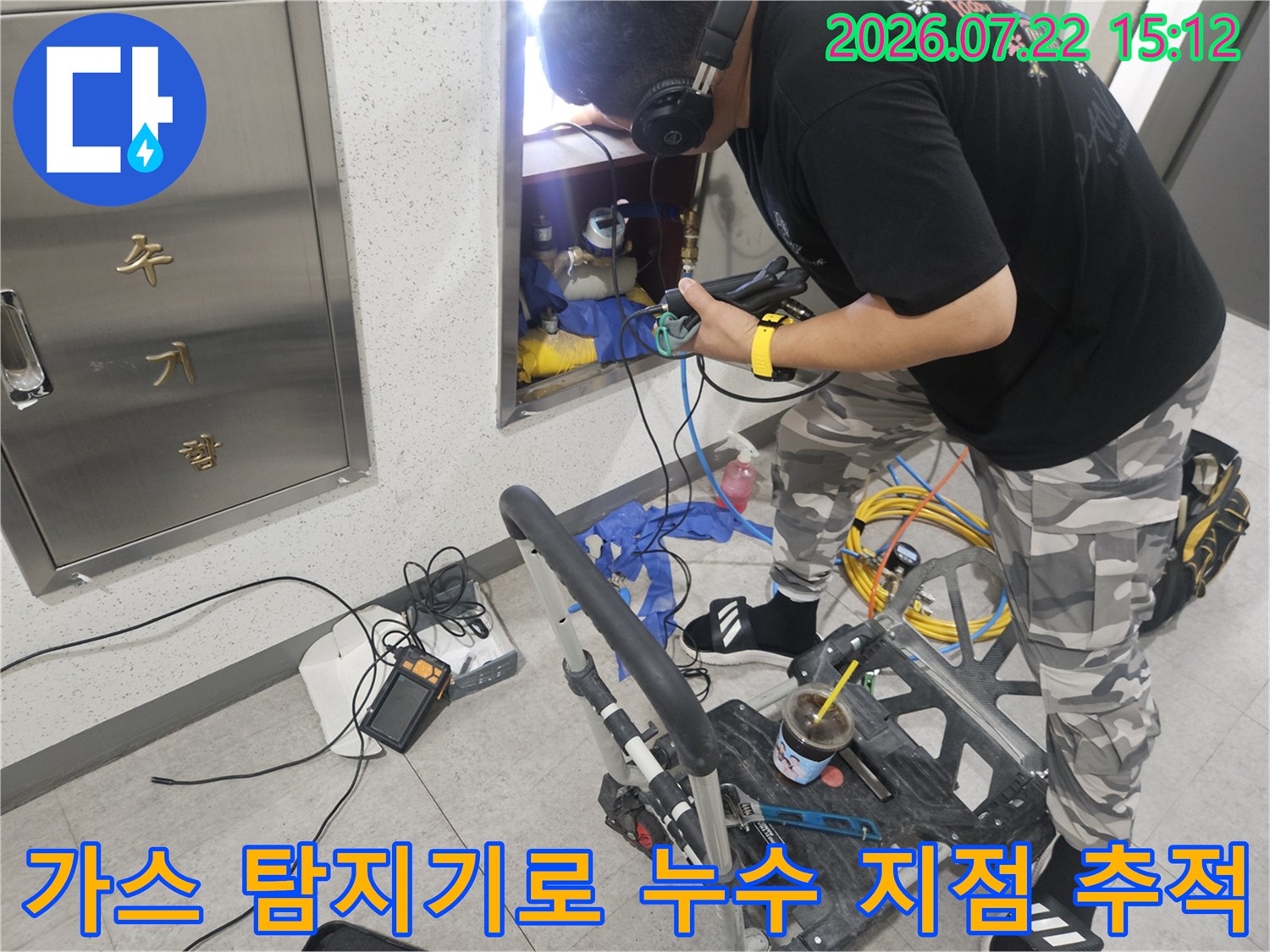 작업자가 헤드셋을 착용하고 가스 탐지 장비를 사용하여 벽면 매립 배관의 누수 위치를 찾는 모습