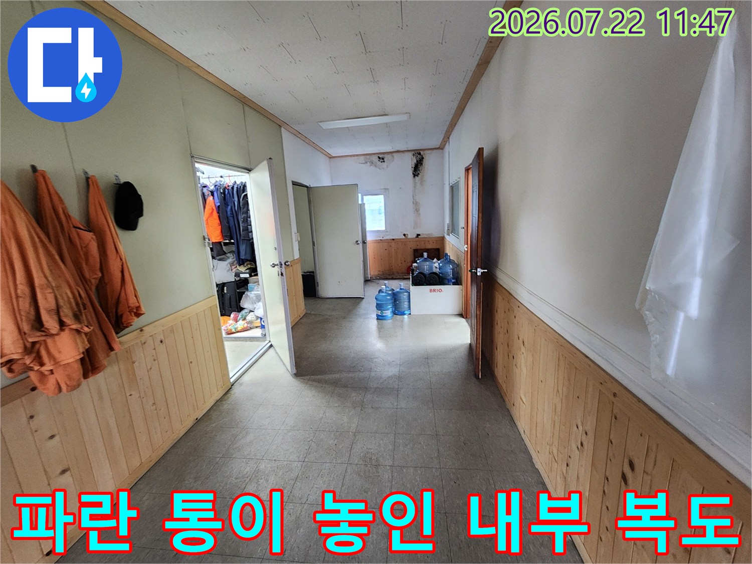흰색 벽과 나무 마감재가 혼합된 공간에 파란색 액체 보관통들이 배치된 모습