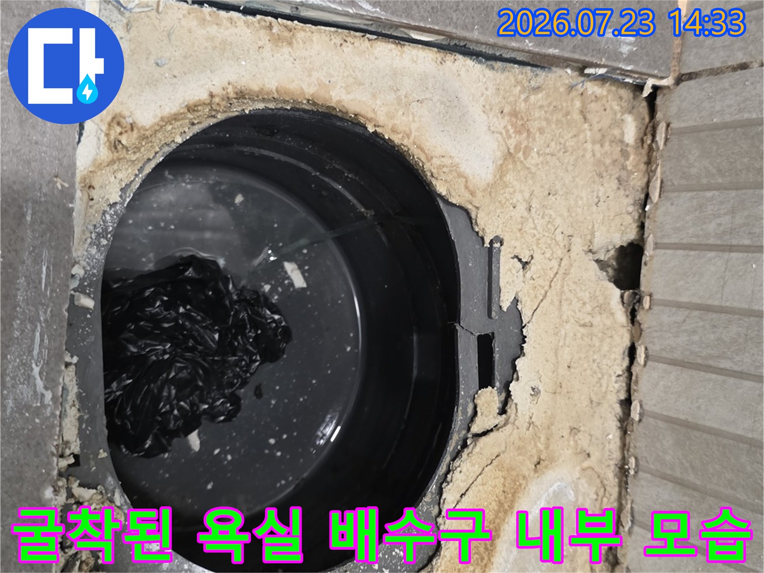 타일 아래 숨겨져 있던 검은색 하수관과 습기로 오염된 주변 시멘트 층-방수 점검 중