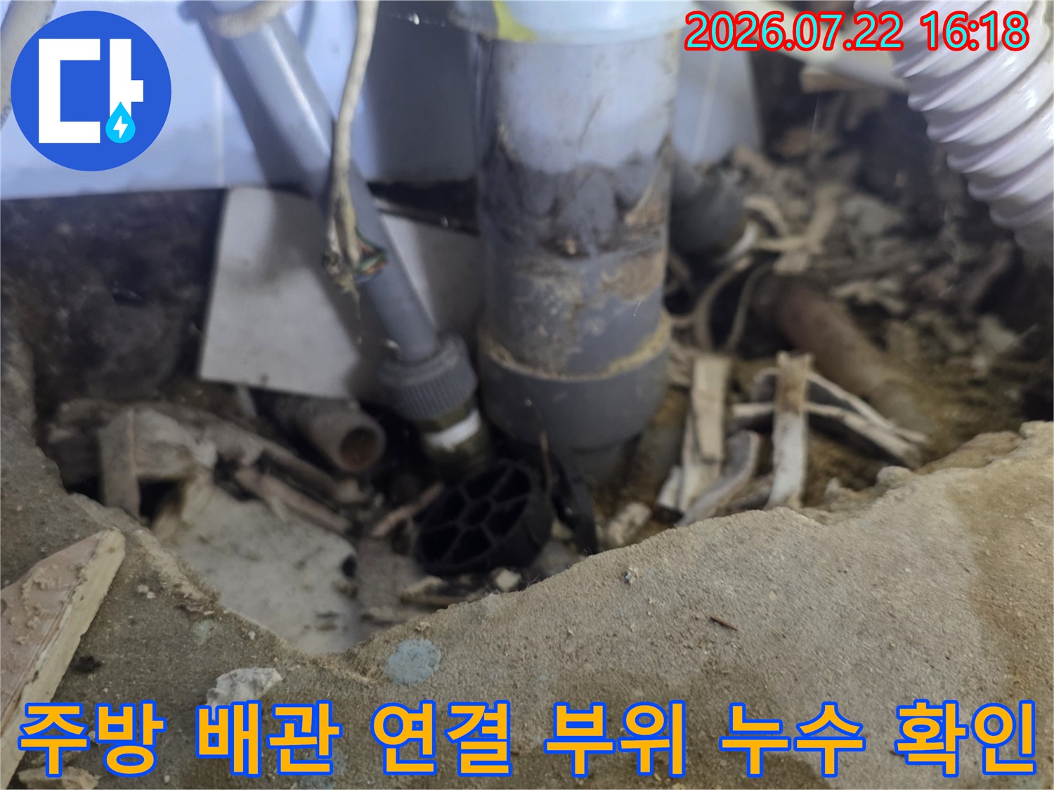 흰색 주름관과 회색 파이프가 연결된-싱크대 하단 배수 시스템 모습