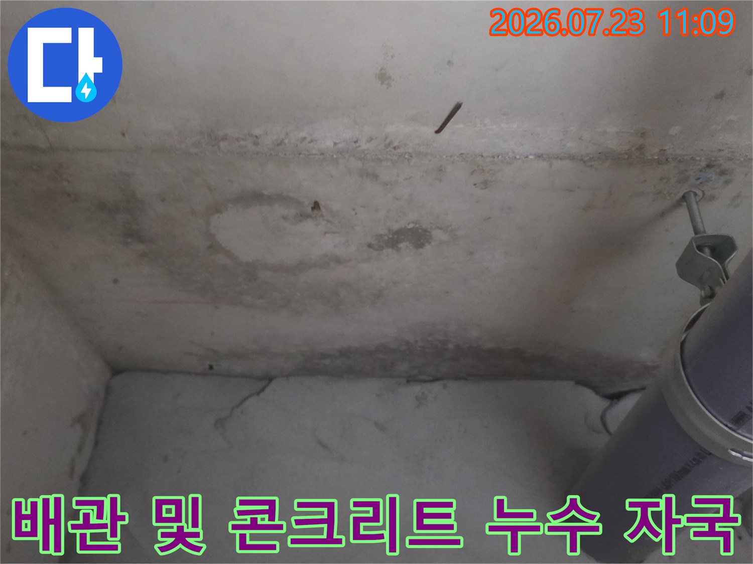 콘크리트 벽면의 젖은 얼룩-우측에 고정된 회색 배수관 모습