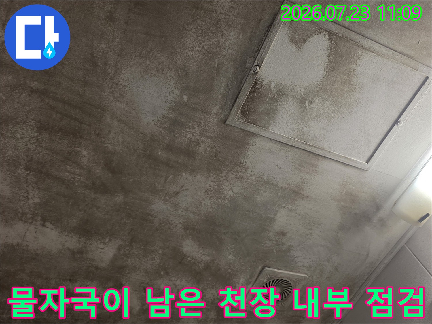 회색빛 콘크리트 천장에 습기로 인한 얼룩과 환풍기 그리고 점검구가 보이는 사진