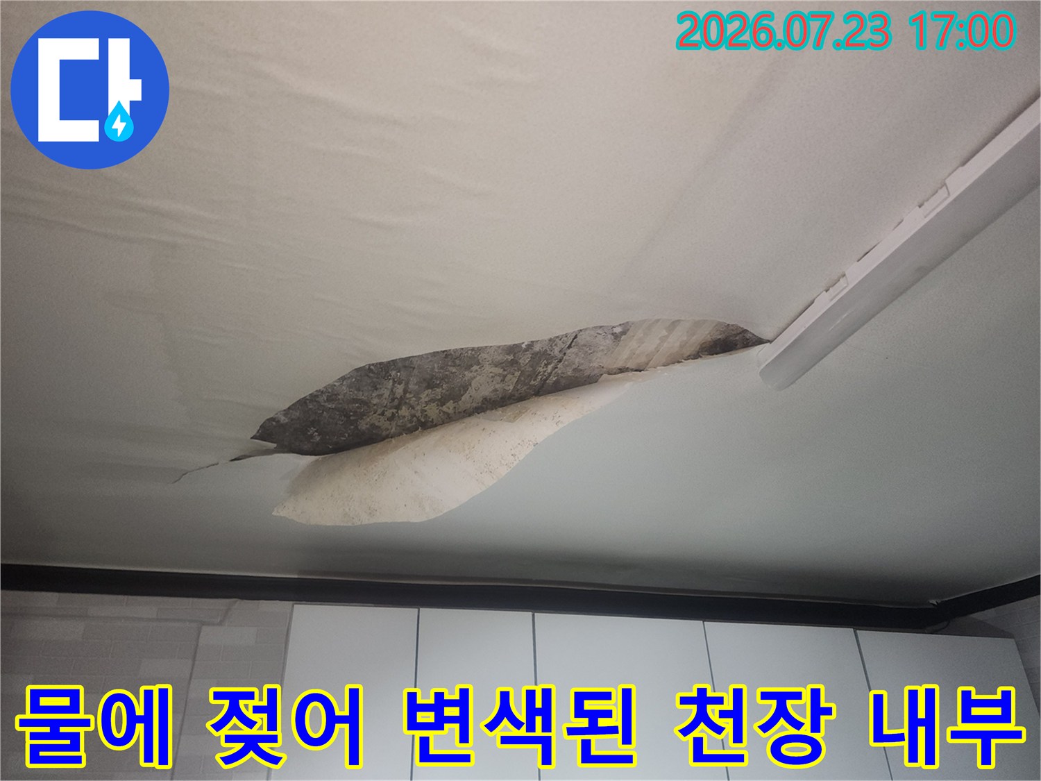 거실-천장의-벽지가-찢어진-부분으로-내부-콘크리트의-짙은-누수-얼룩이-보이는-사진