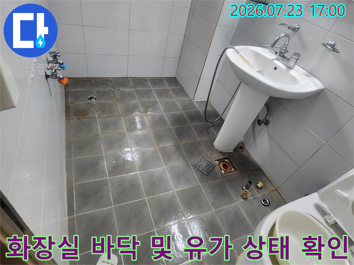 흰색 세면대와 변기가 설치된 욕실-바닥 타일의 오염과 배수구 주변 상태를 보여주는 사진