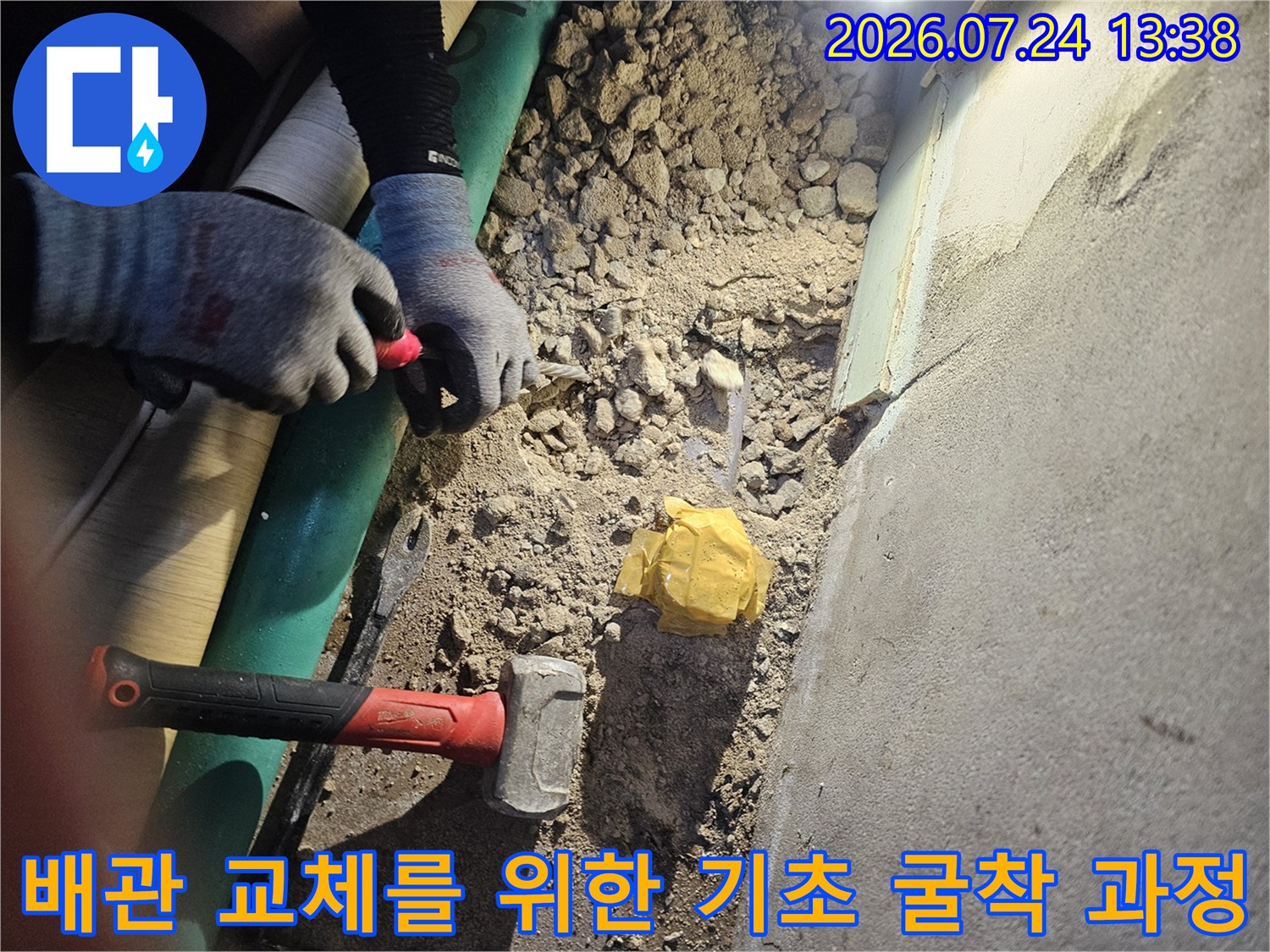 망치와 수공구를 사용하여 바닥 콘크리트를 제거하고 배관을 찾는 작업 현장