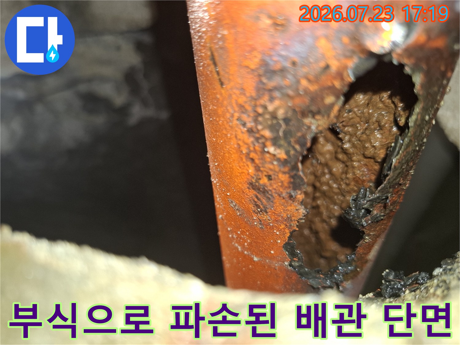 부식되어 내부 물질이 드러나고 구멍이 크게 뚫린 오렌지색 배관의 모습