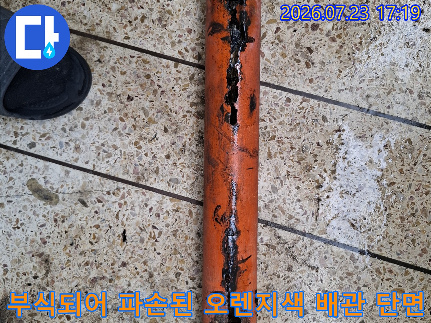 표면이 검게 변하고 갈라짐이 심한 부식된 상태의 오렌지색 배관-누수 발생 지점