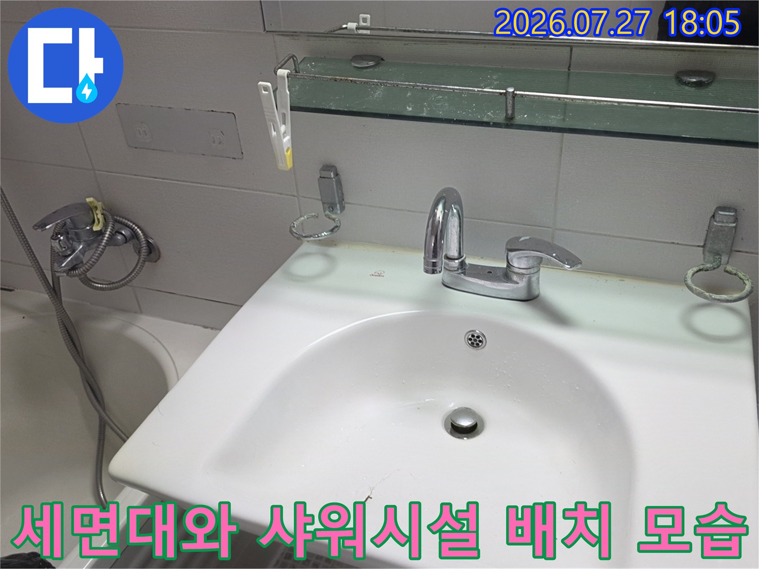 욕실 내 세면대-거울 선반-샤워기가 일렬로 배치된 내부 전경