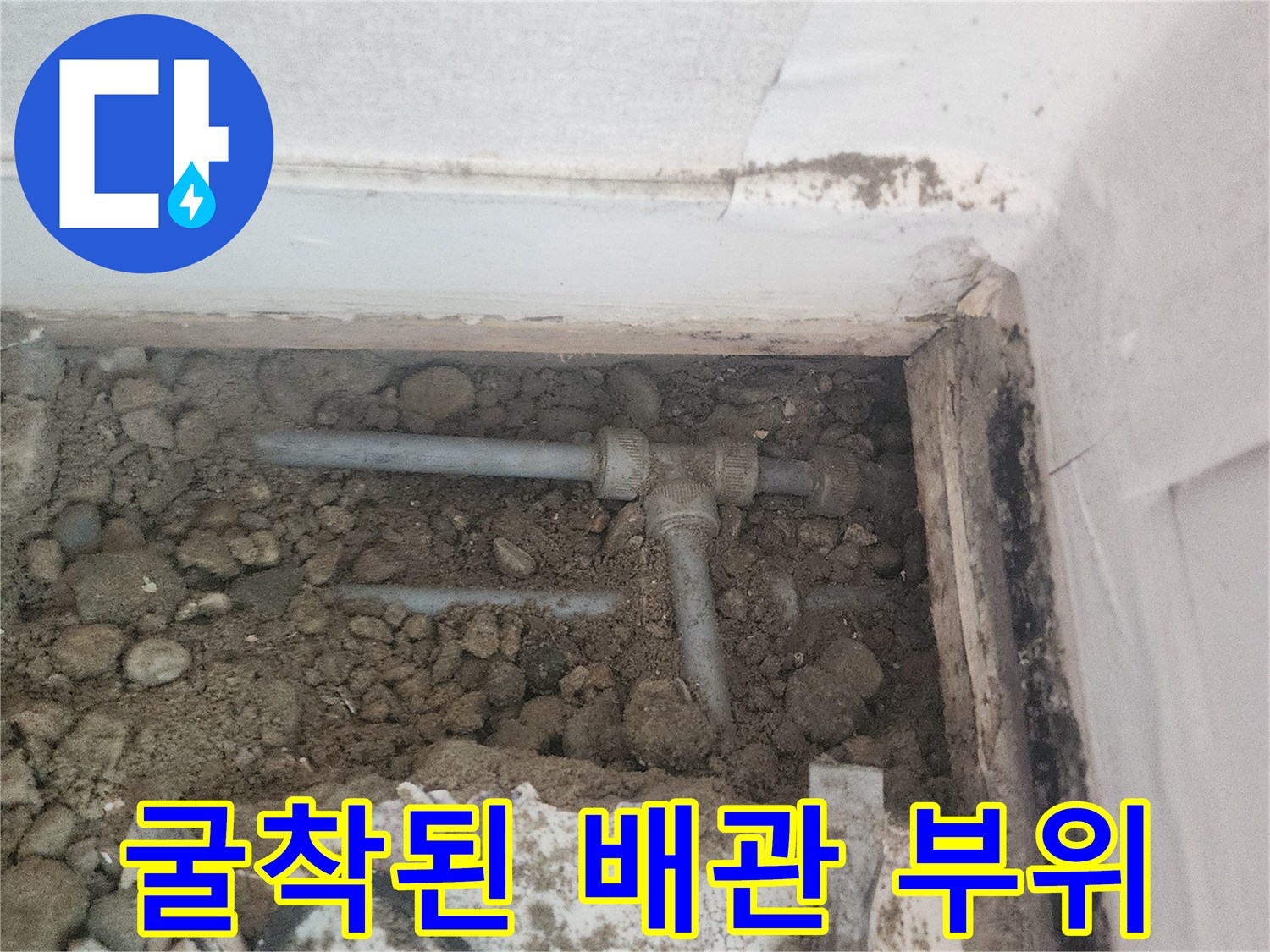 자갈과 흙 사이로 드러난 손상된 수도 배관의 모습