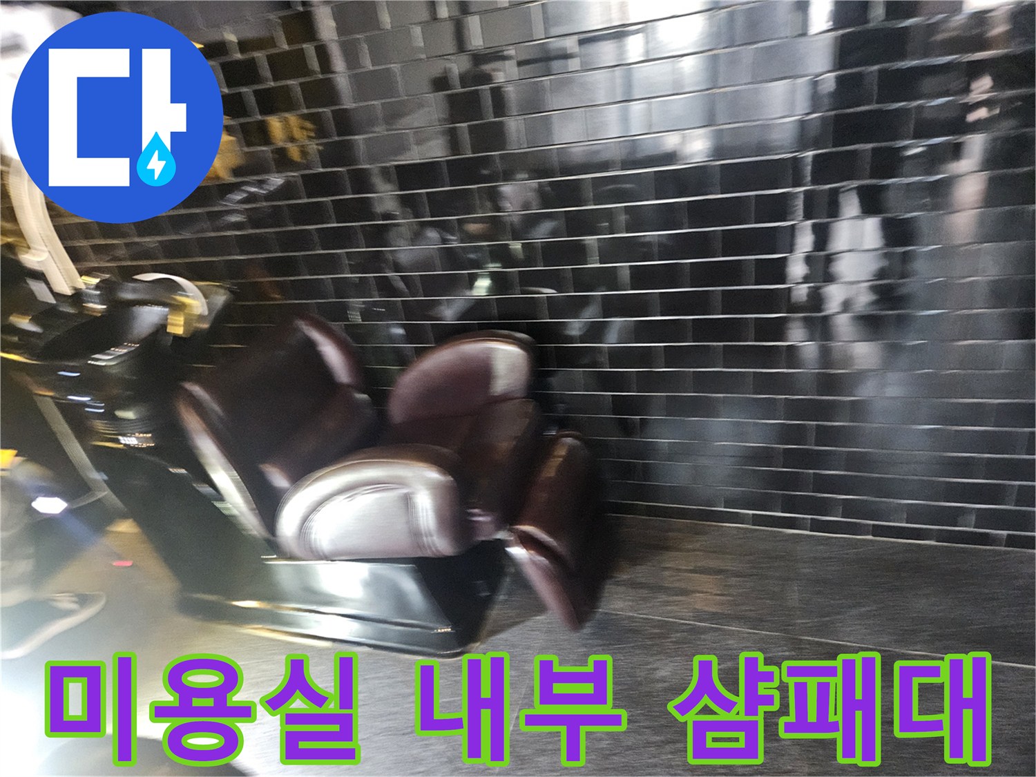 어두운 색상의 타일 벽면과 미용실 샴푸 의자 모습