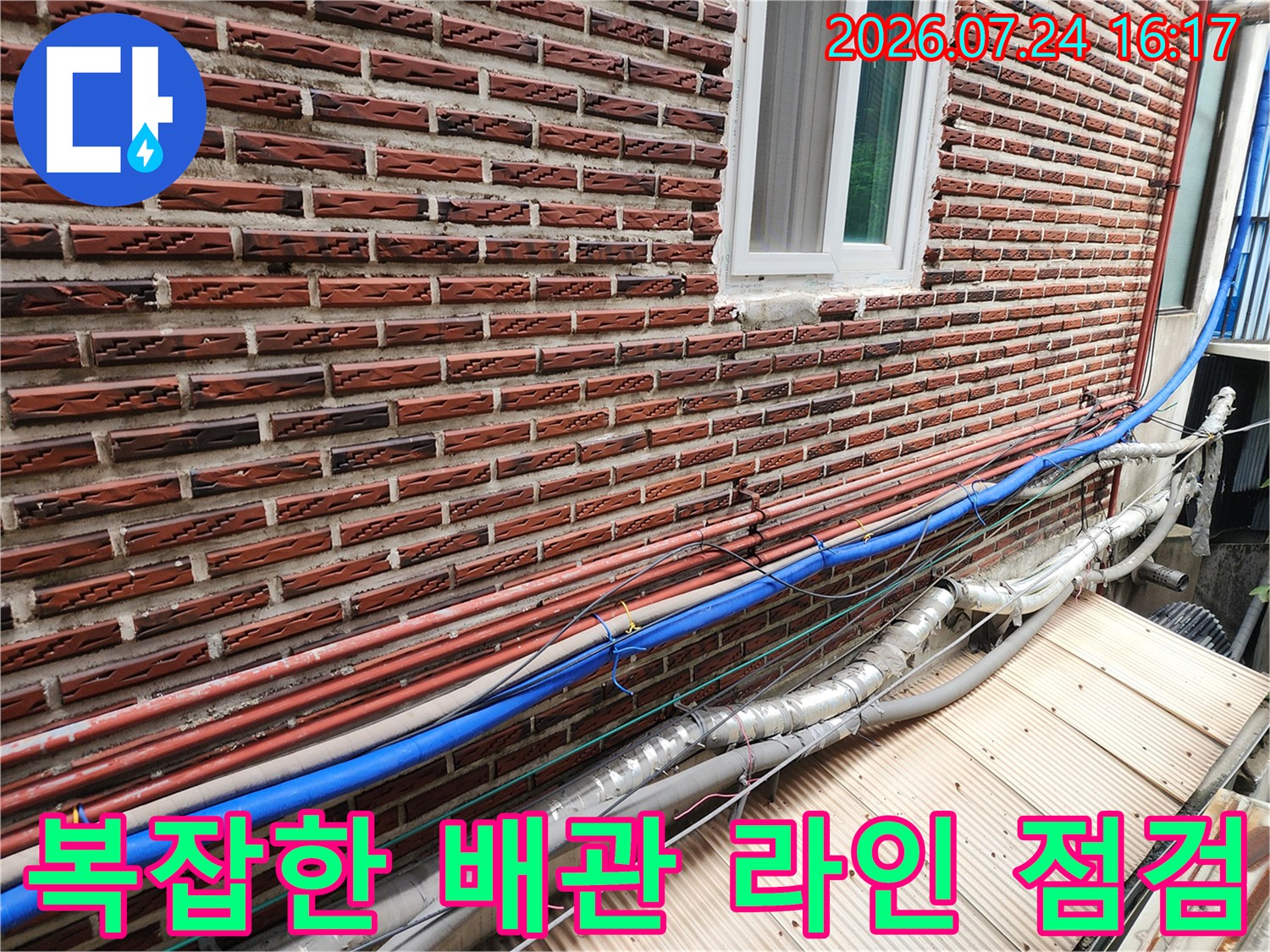 벽돌 벽면에 노출된 파란색과 은색 단열재로 감싸진 수도 배관