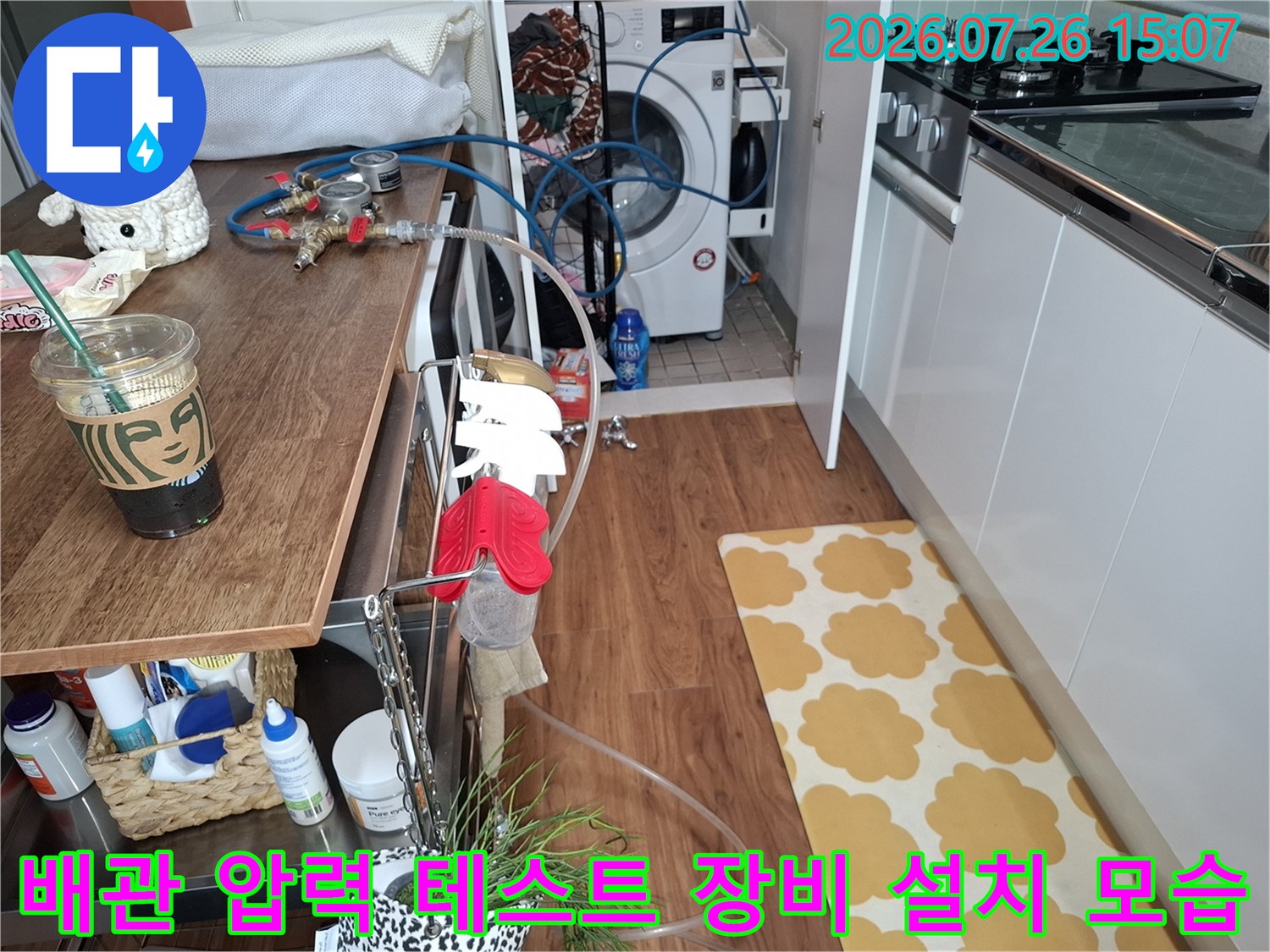 주방과 세탁실 사이 공간에 배치된 파란색 공압 테스트 호스와 정밀 측정 장비-누수 지점 탐지를 위한 준비 과정