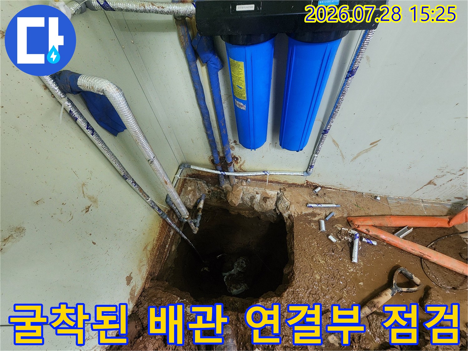 흙이 묻은 배관과 파란색 필터 장치가 배치된 누수 보수 구역