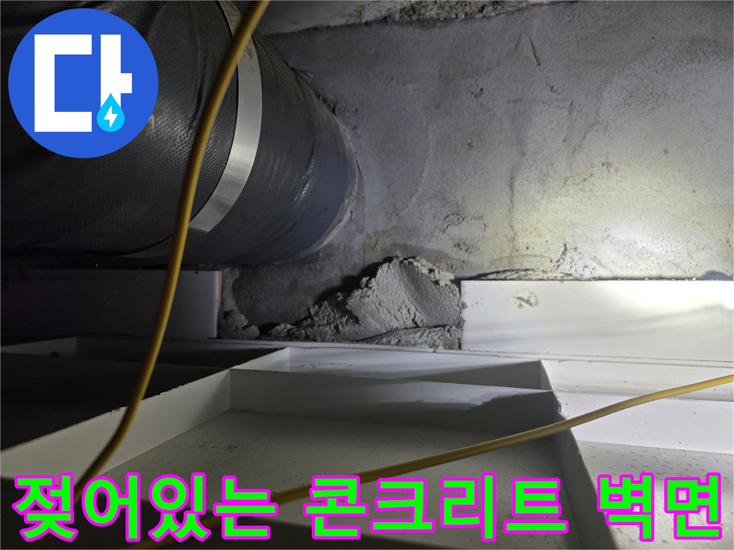 물에 젖은 듯한 회색 콘크리트와 은색 배관의 모습