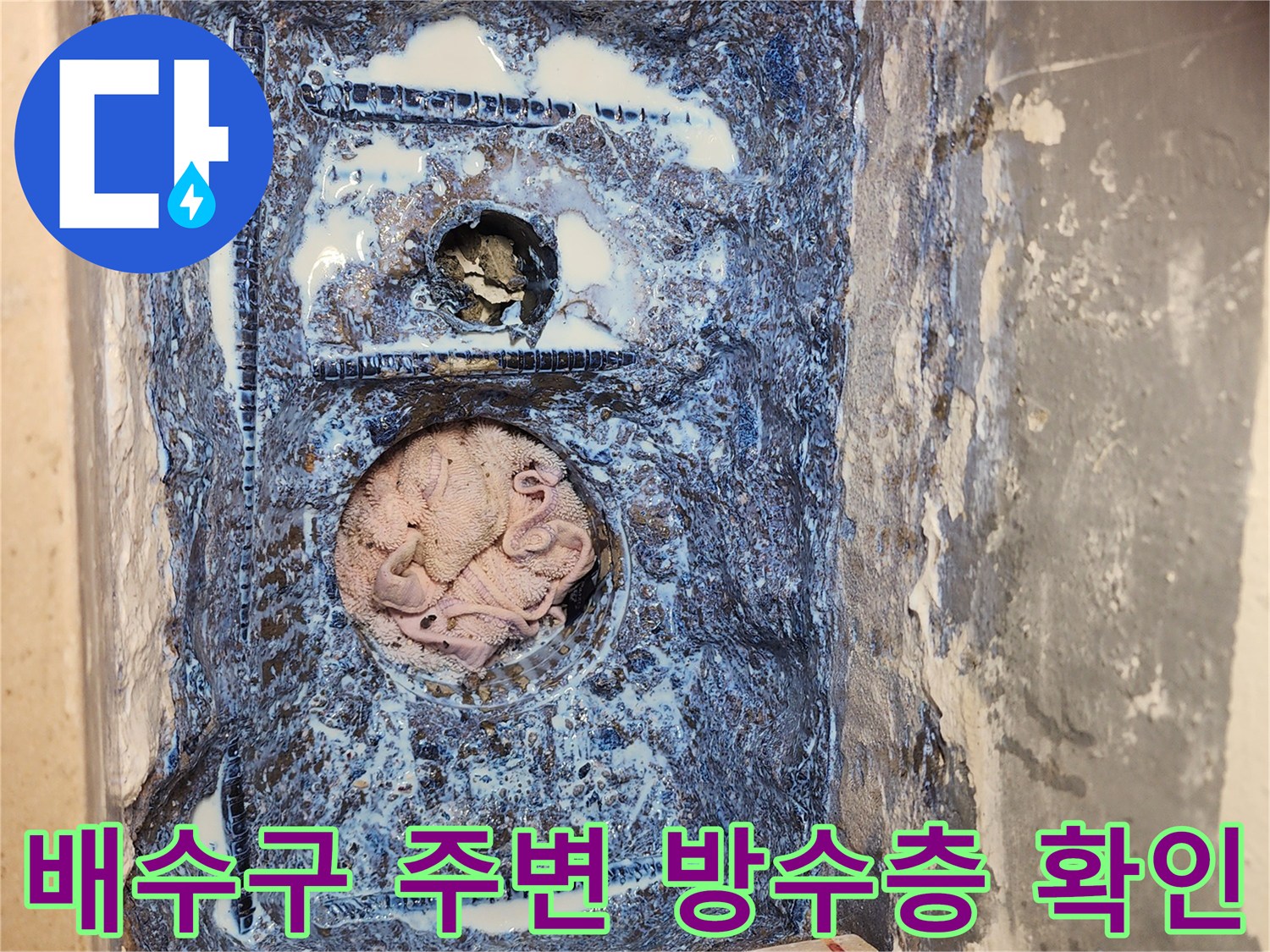 세탁실 배수구 주변의 파손된 방수층과 노출된 배관 상태를 보여주는 사진입니다.