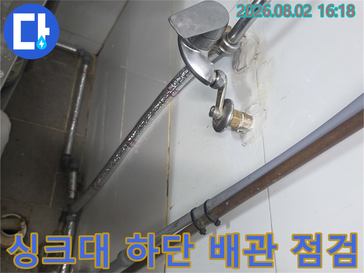 싱크대 아래 노출된 금속 배관과 수전 연결 부위를 정밀하게 점검하는 장면