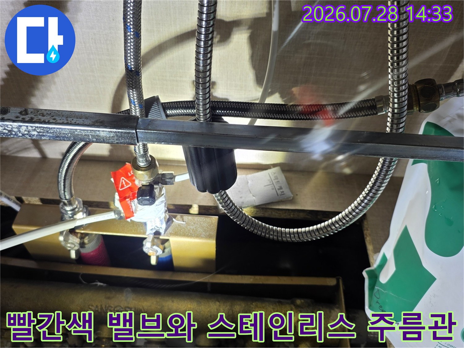 분배기에 연결된 빨간색 조절 밸브와 은색의 유연한 스테인리스 호스-배관 시스템