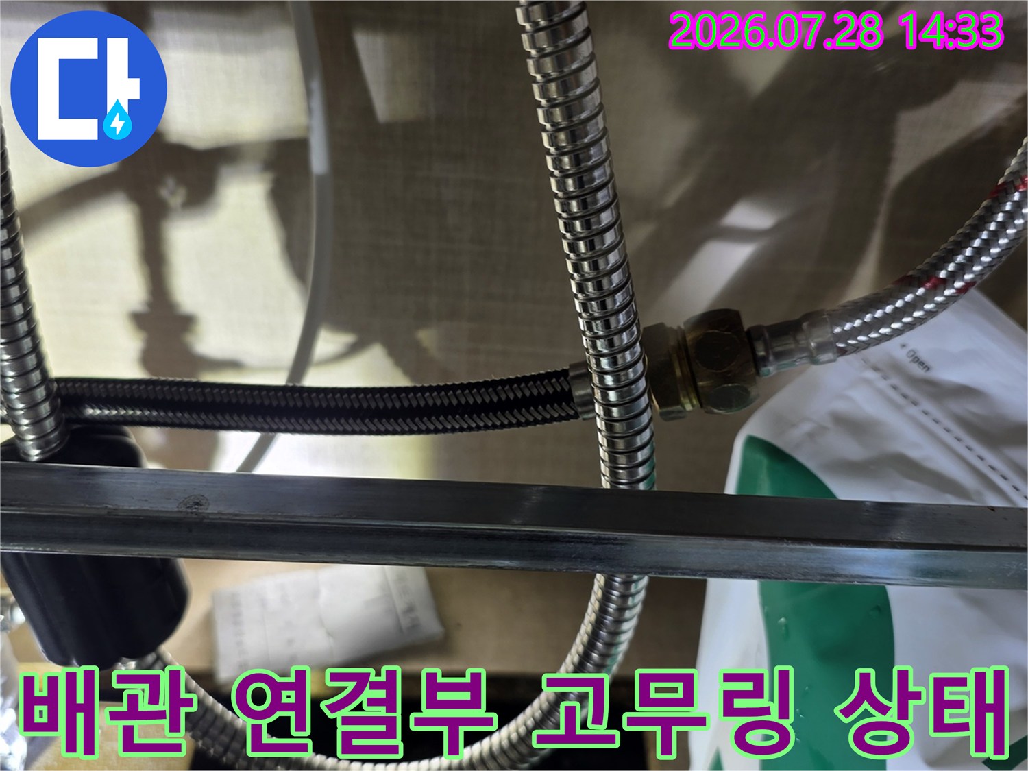 스테인리스 배관의 체결 너트 부분과 바닥에 떨어진 노후된 검은색 고무 패킹 사진