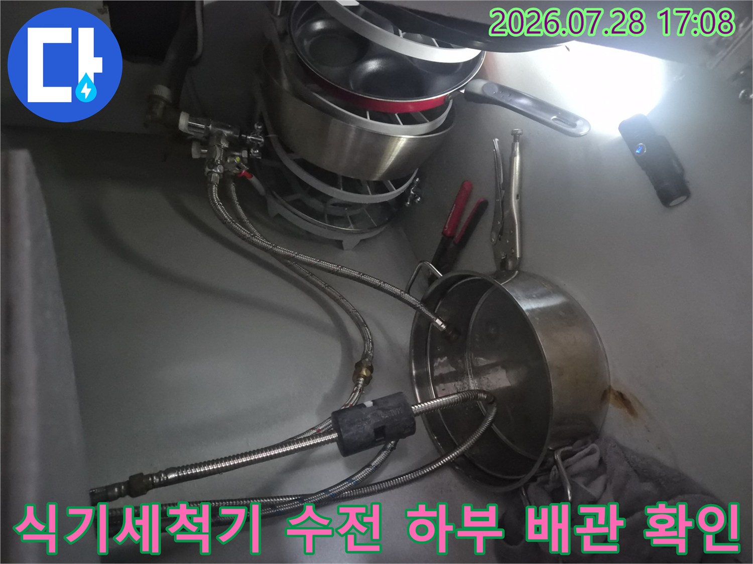 싱크대 아래 위치한 식기세척기용 분배 밸브와 연결 부품의 상태를 점검하는 모습