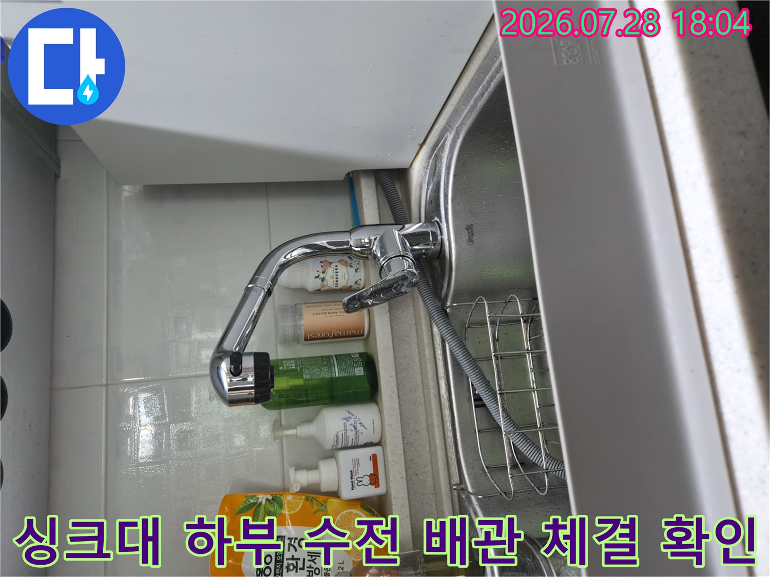 싱크대 아래쪽 노출된 수전 연결 어댑터와 호스 구간의 누수 여부를 점검하는 모습