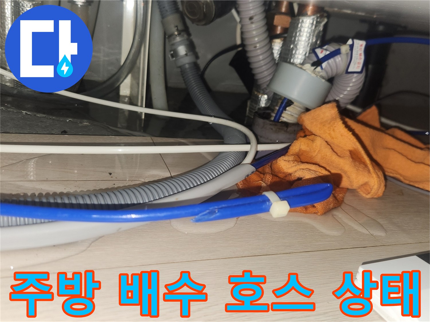 싱크대 밑 배관 연결 부위와 파란색 호스가 보이는 모습