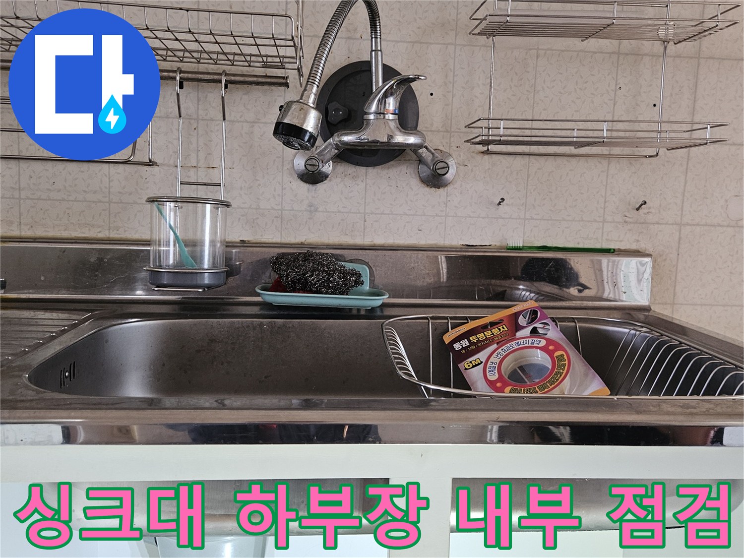 싱크대 아래쪽 배관과 수전 호스가 복잡하게 연결된 모습