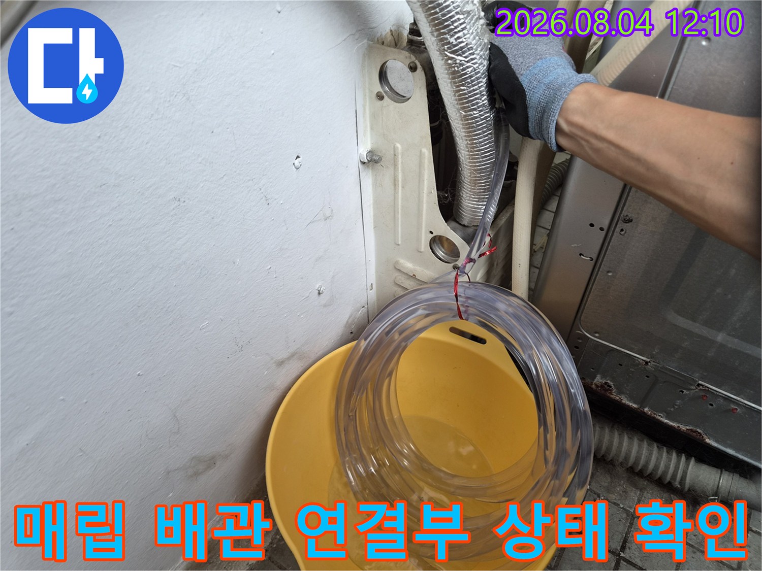 노출된 에어컨 배관과 노란 양동이 옆의 점검 작업 모습