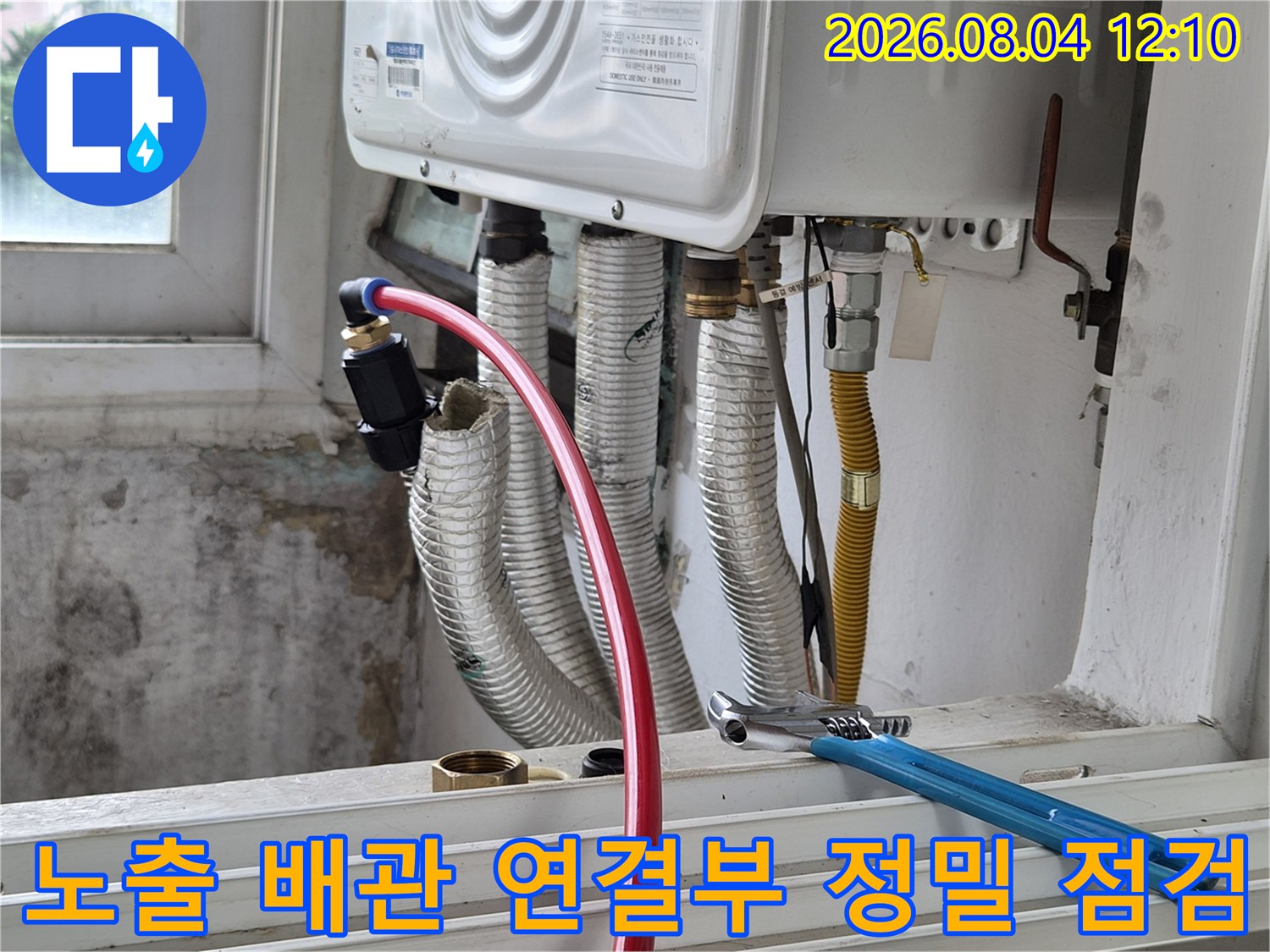 파란색 렌치 도구를 사용하여 에어컨 배관의 연결 부위를 점검하는 현장 사진