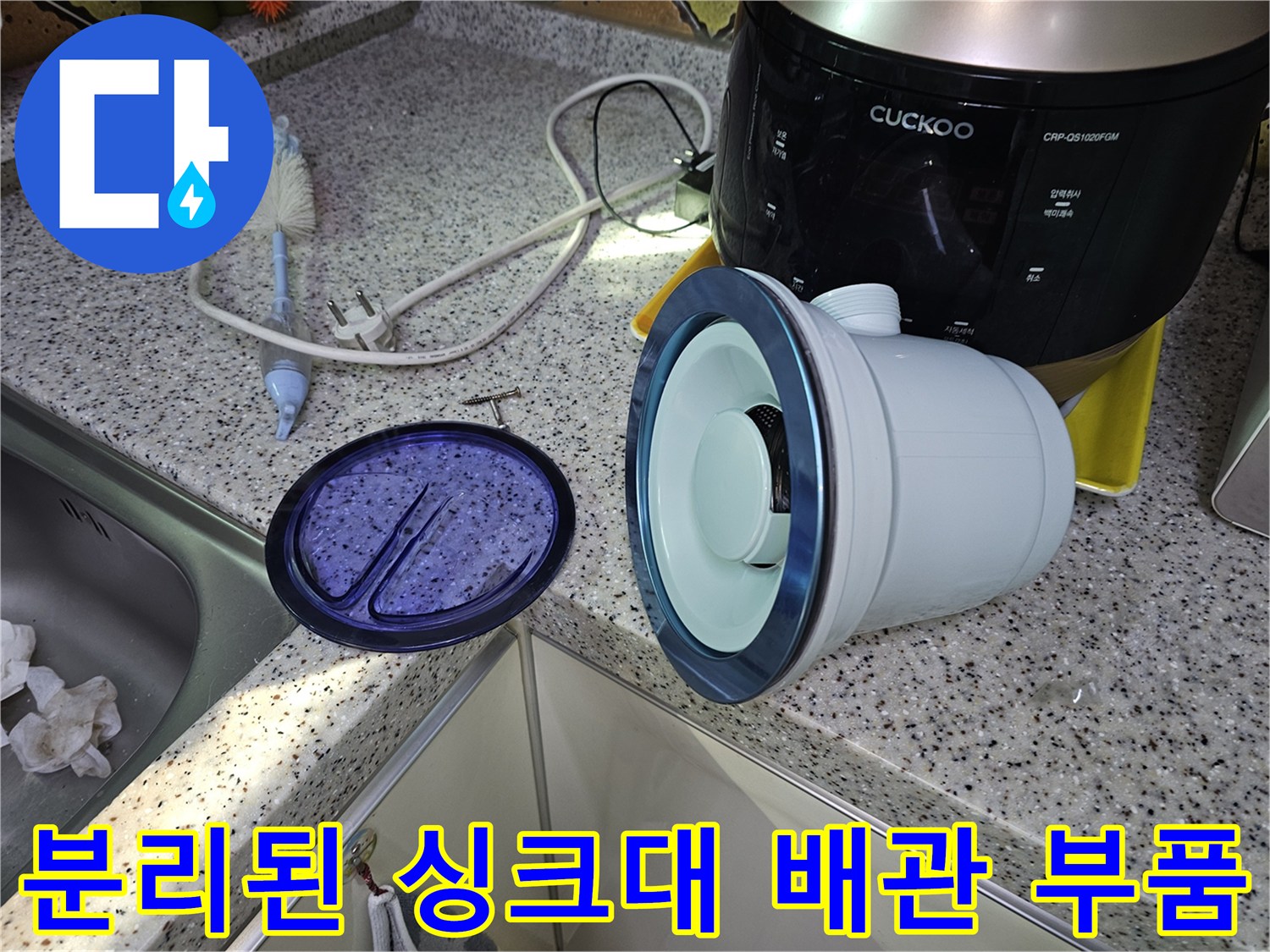 싱크대 하부의 분리된 배관 부속과 밥솥이 놓인 현장 모습입니다.