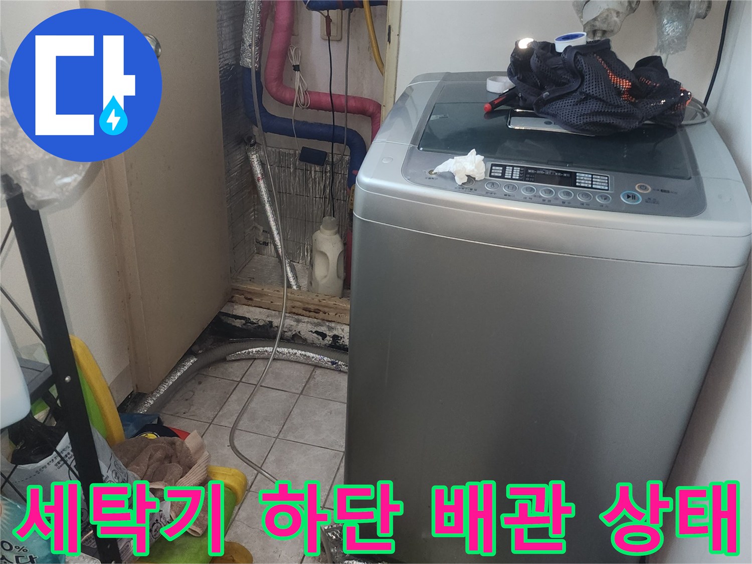 세탁기 뒤편 좁은 공간의 수도 분기 배관과 연결 부위를 보여줍니다.