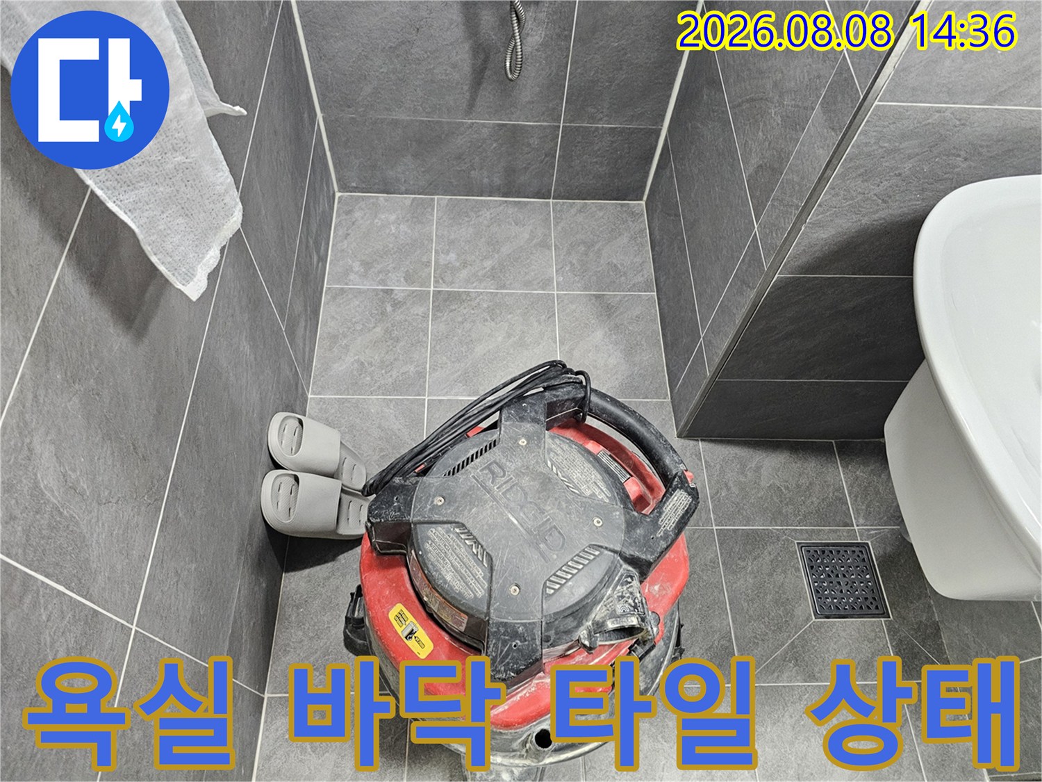 회색 욕실 타일과 변기 옆의 산업용 청소 도구
