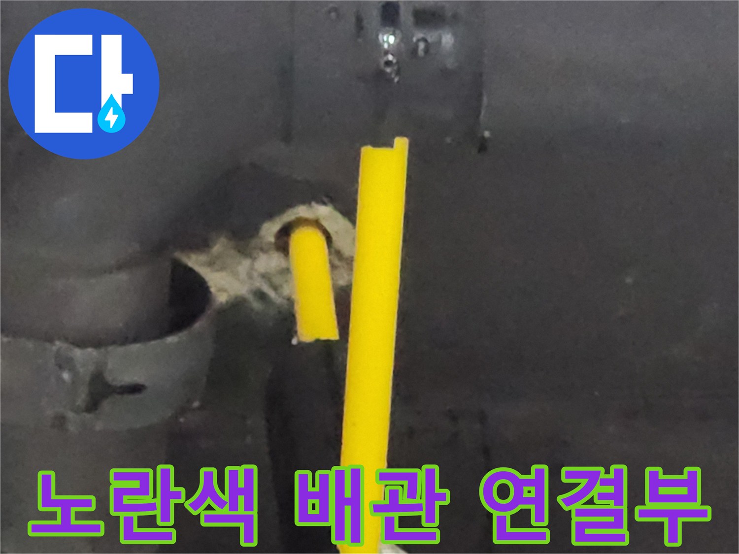 싱크대 하부의 노란색 급수 배관과 벽면 관통 부위 모습
