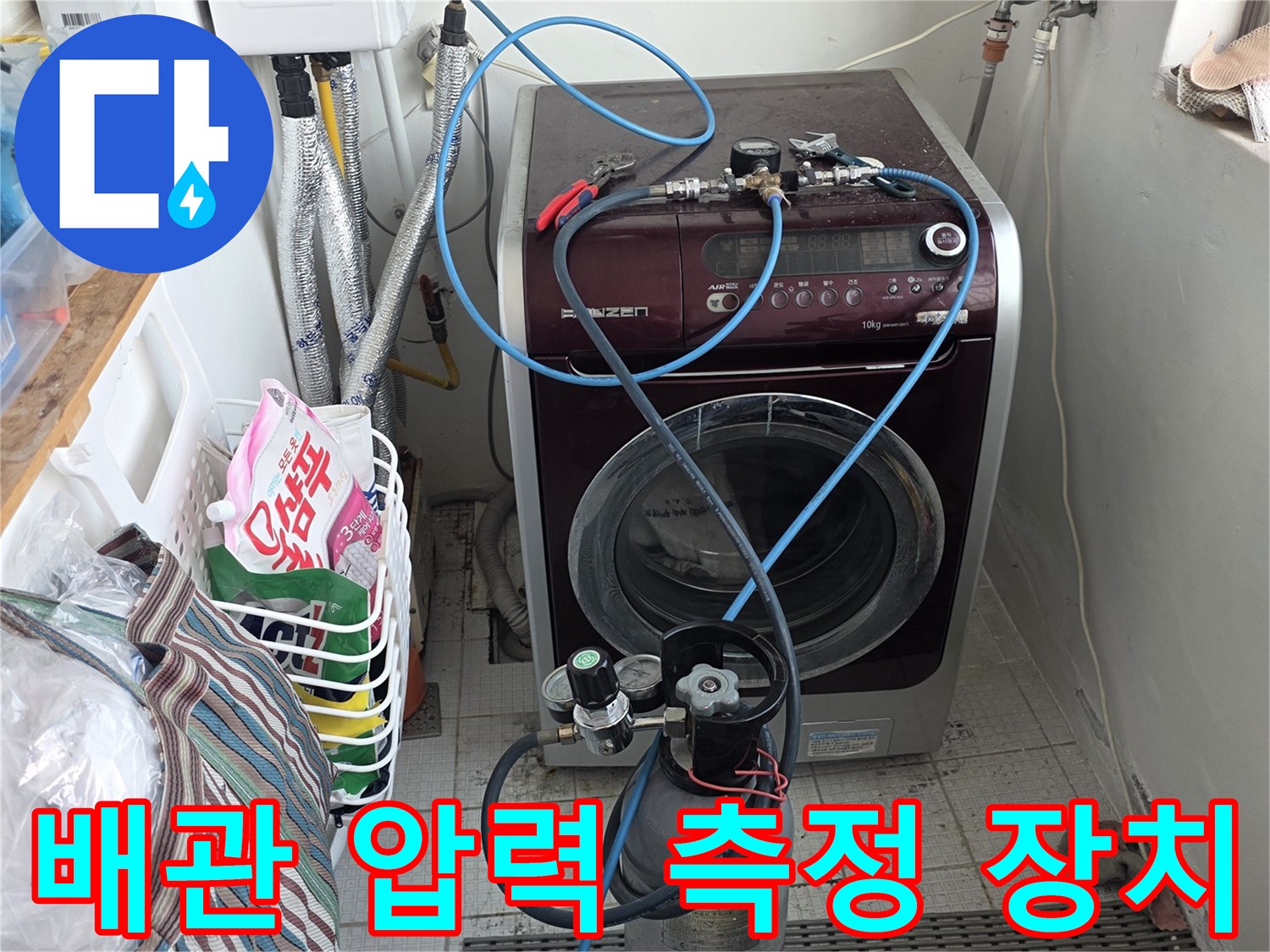 세탁실 벽면 배관에 연결된 공압 테스트용 게이지와 파란색 호스