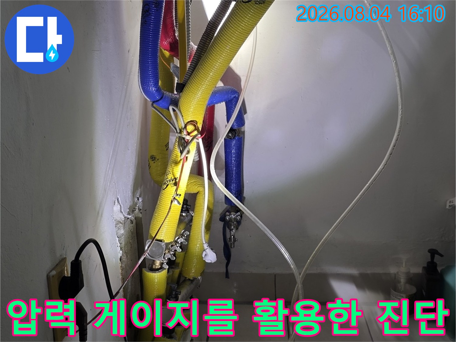 공구와 호스를 연결하여 배관 압력을 실시간으로 측정하는 기술적인 장면