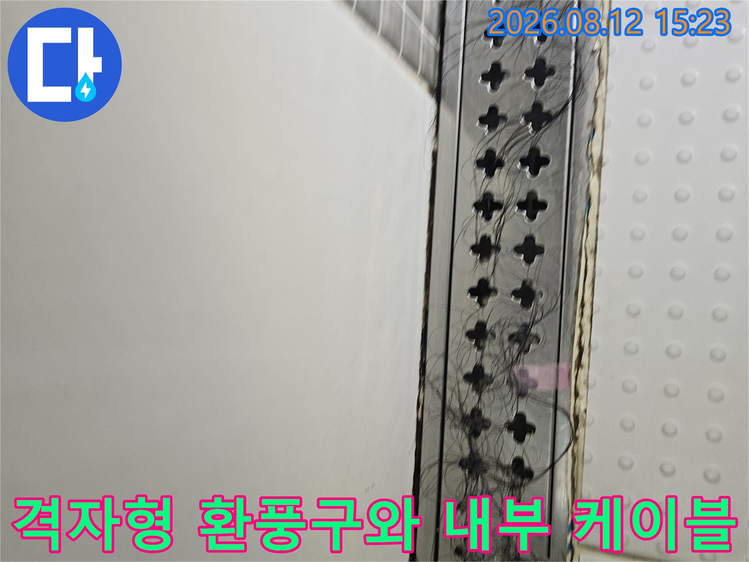 흰색 천장 패널 아래쪽의 검은 전선들과 격자무늬 모양의 환기 장치 사진