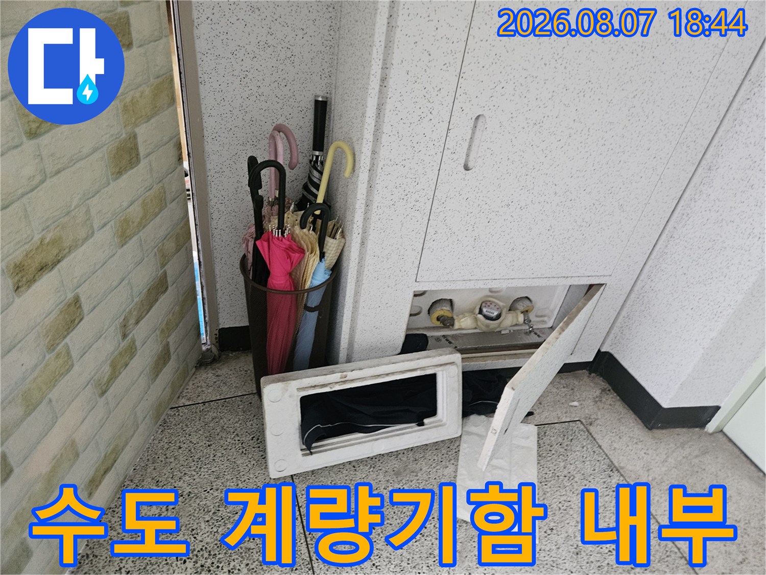 열려 있는 수도 계량기함과 배관 연결 부위