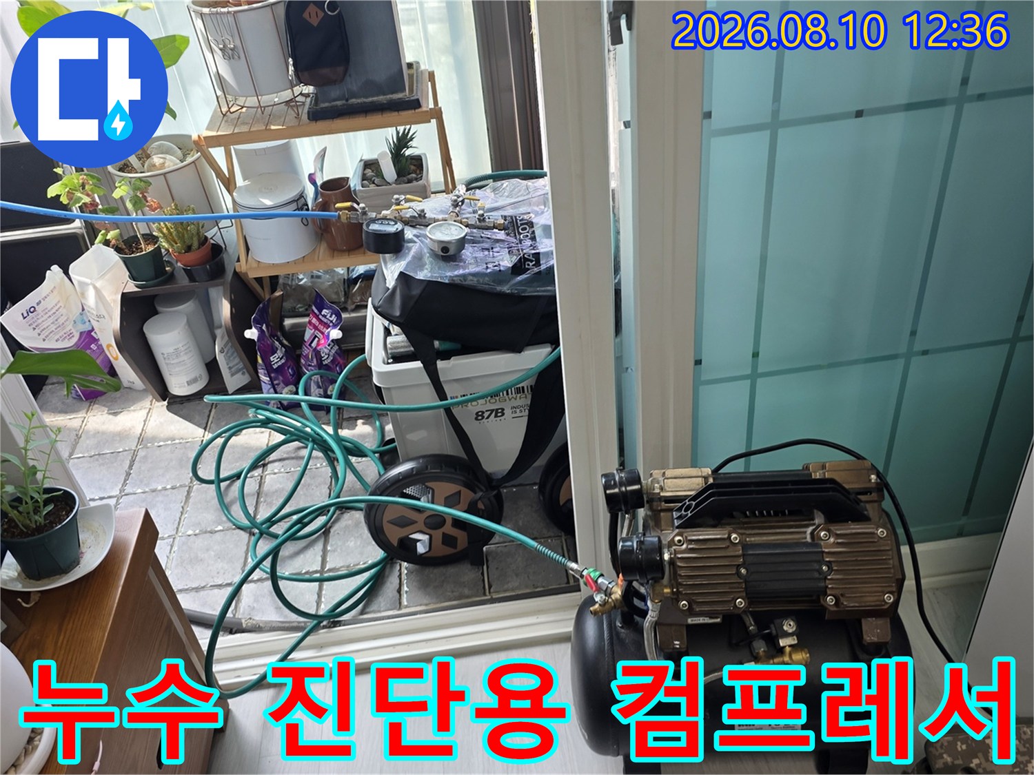 베란다 작업 현장에 설치된 누수 탐지용 에어 컴프레서와 호스 라인
