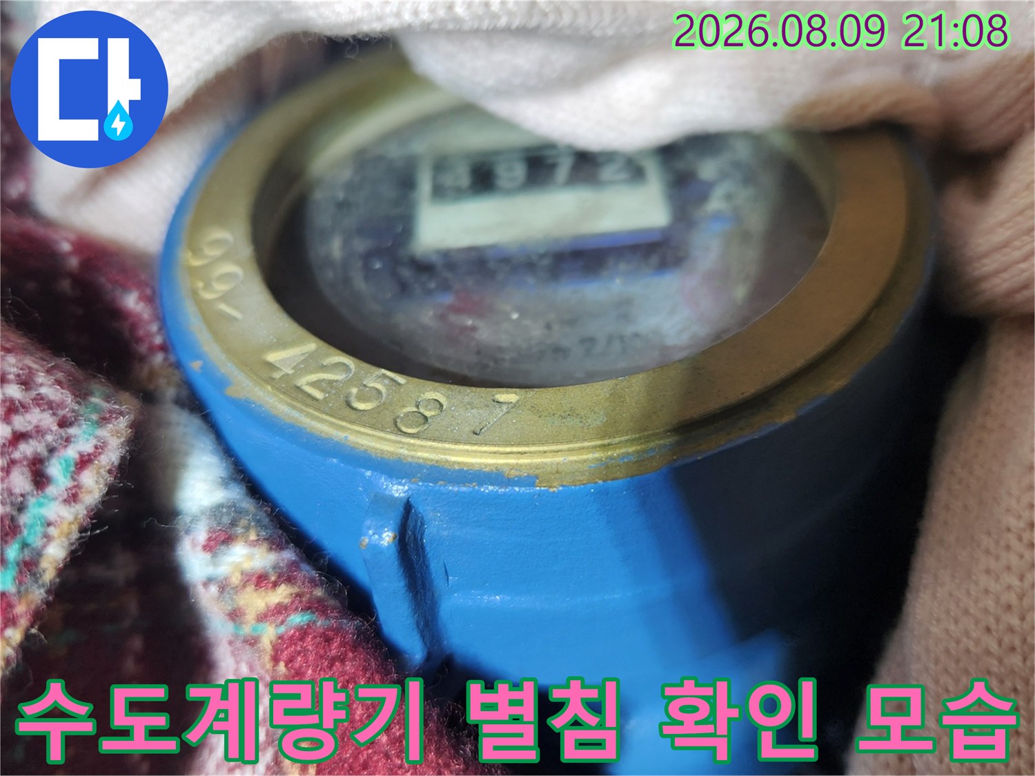 파란색 수도계량기 내부의 숫자판과 별 모양의 회전 침을 근접 촬영한 사진