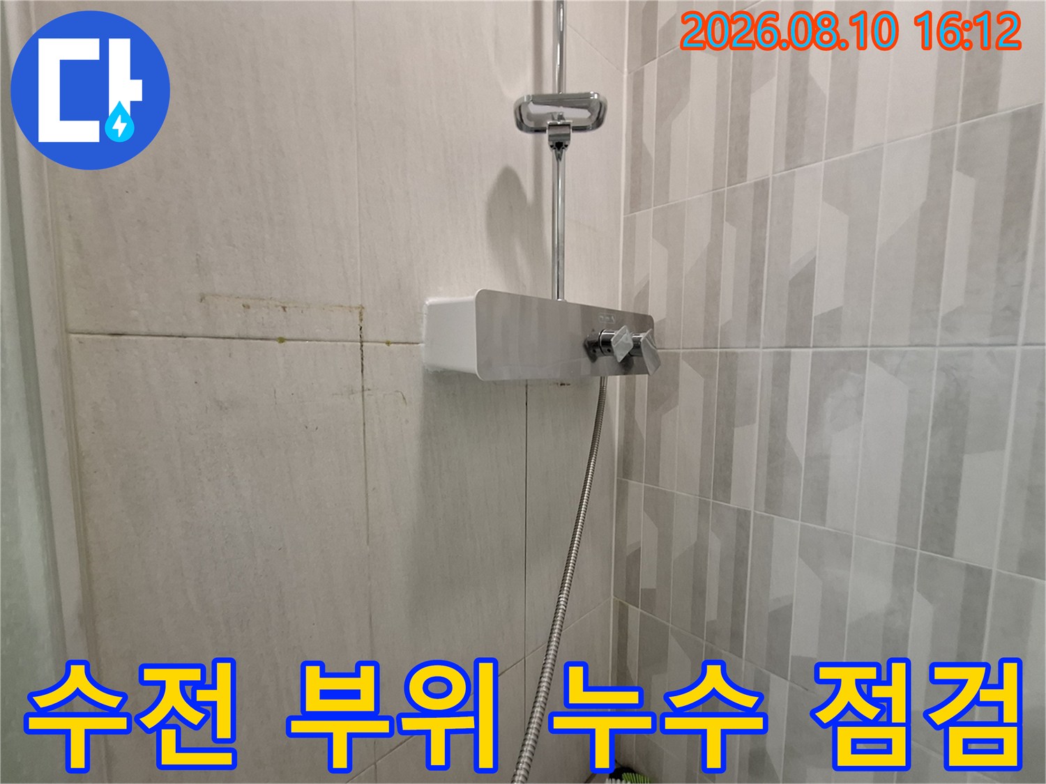 화장실 벽면에 설치된 샤워기 수전과 호스 근접 사진