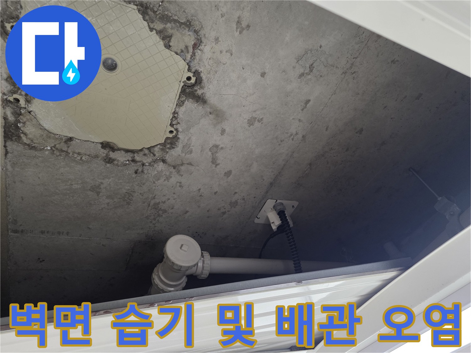 축축하게 젖은 콘크리트 벽면과 노출된 흰색 배관 부속