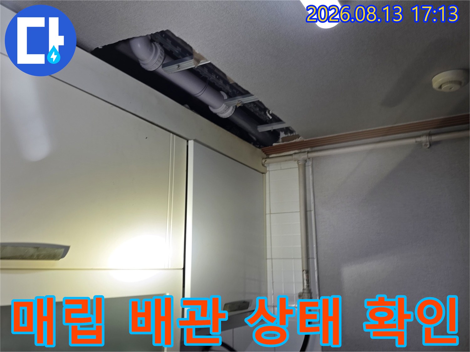 주방 상부장 뒤 공간에 노출된 하수 배관의 상세 모습