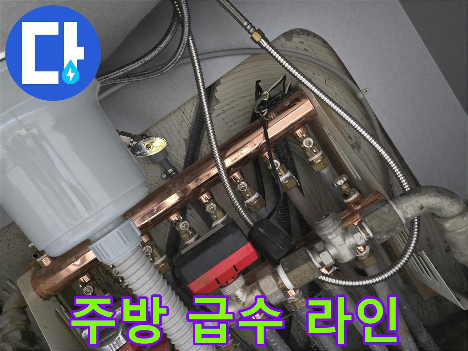 금속 배관과 검은색 호스가 결합된 싱크대 하부 구조물