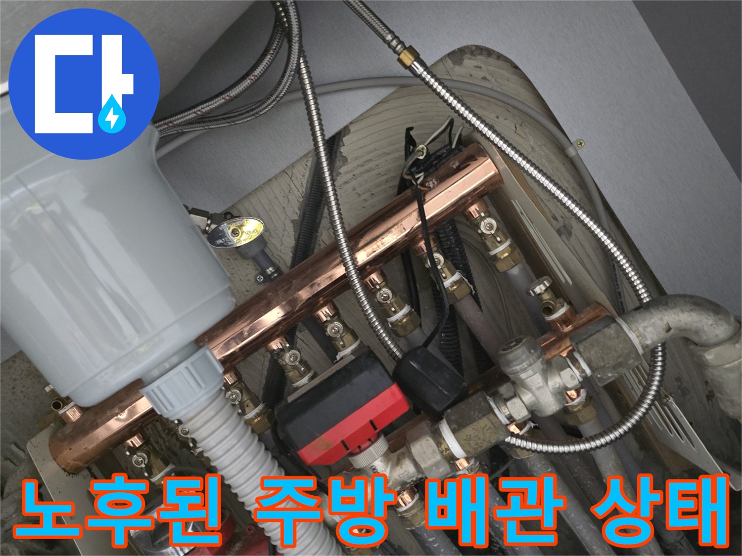 싱크대 하부장 내부의 낡은 수전 연결 호스와 급수 부품들