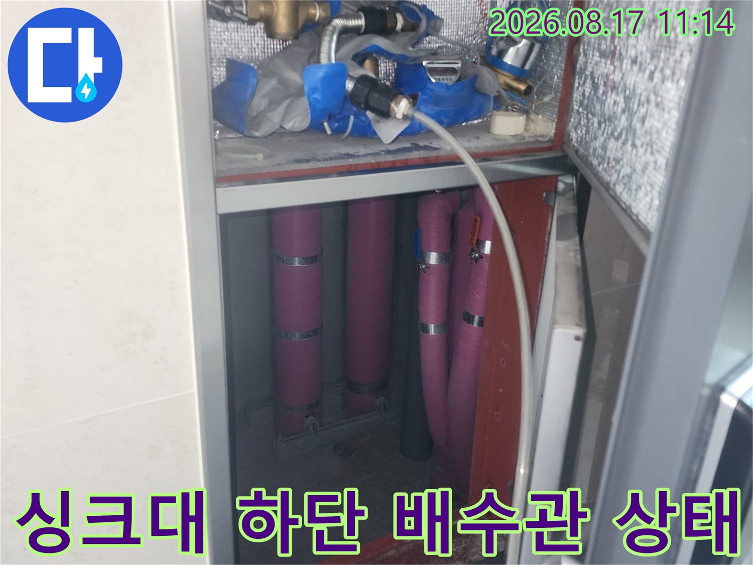 싱크대 아래쪽 금속 밸브와 분홍색 배수 호스의 누수 여부 확인 작업