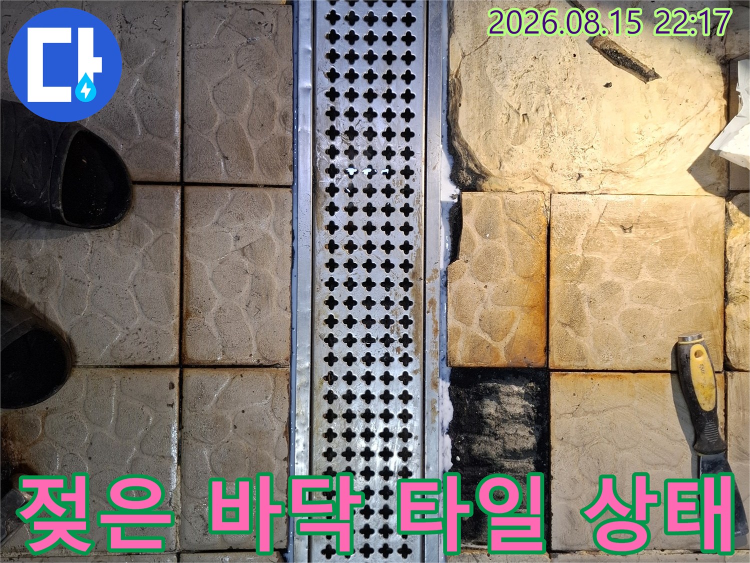 금속 트렌치 주변의 젖어 있는 타일과 작업 도구들