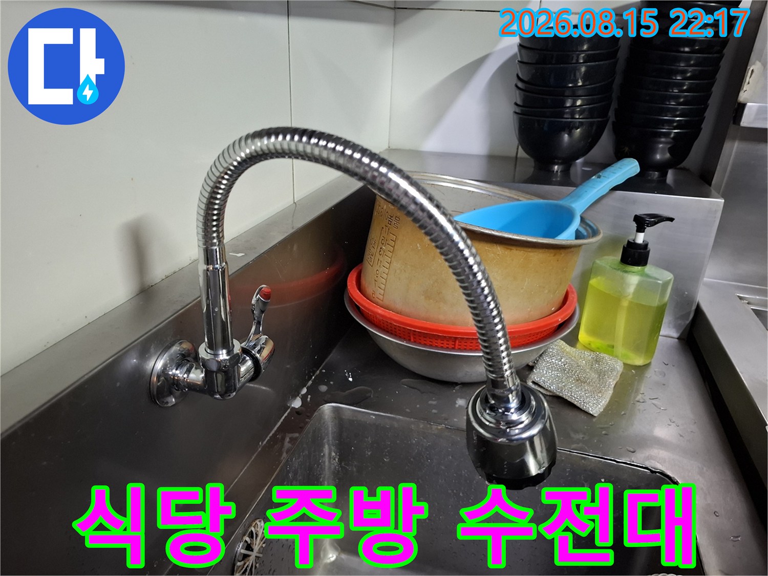 식당 내부 싱크대의 스테인리스 수전과 주변 용기들입니다.